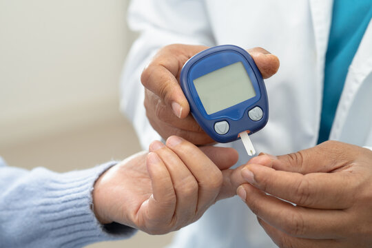 Doctor check diabetes from finger blood sugar level with finger lancet.