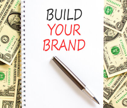 Build your brand words symbol. Concept words Build your brand on beautiful white note. Beautiful dollar bills background. Business and build your brand concept. Copy space.