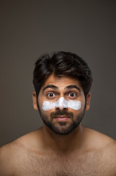 AN EXPRESSIVE YOUNG MAN LOOKING AT CAMERA WHILE GROOMING HIMSELF