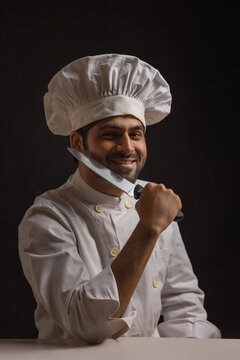 A HAPPY PROFESSIONAL CHEF SITTING AND POSING IN FRONT OF CAMERA