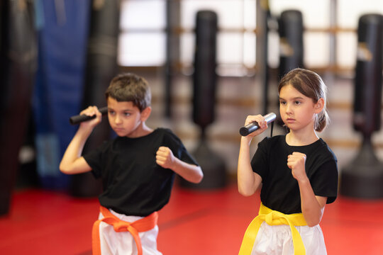Boy and a girl, teenagers with nunchucks in their hands. Training in martial arts for children.