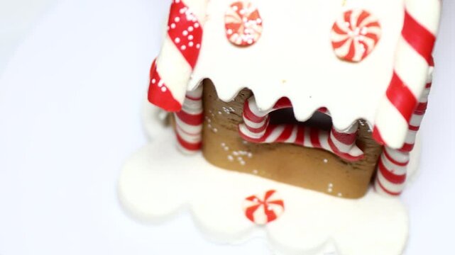 A close-up shot of a gingerbread house on a plate, perfect for holiday or Christmas-themed uses. Rotating in a circle