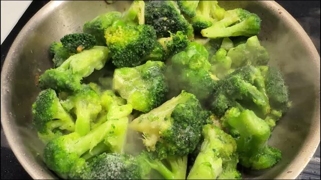 Fresh broccoli florets frying in a pan with oil. Close-up of a healthy vegetable being cooked, showcasing a simple homemade meal preparation process.