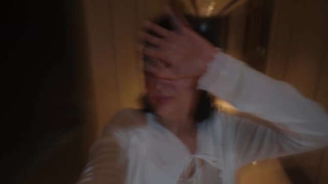 Asian woman walking along hallway covering face from flashing bright lights motion blur disoriented footage