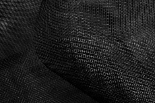 Crumpled black fiberglass mosquito net fabric. Modern abstract dark background with grid pattern