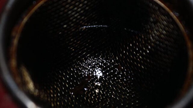 A close up view of a metal strainer with intricate details. Rotating in a circle