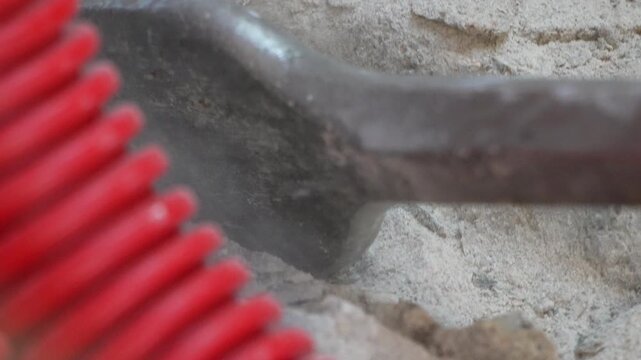 Industrial hammer drill breaking up concrete beside flexible red tubing in close up shot