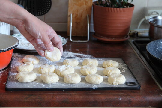 The process of making homemade cheesecakes. A close-up of a hand placing a raw cheesecake on a floured surface. Traditional Eastern European cuisine.
