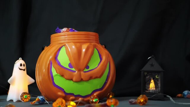 Halloween jack-o-lantern candy bucket filling with wrapped sweets