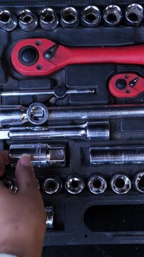 Socket wrench set in a black tool case with a hand picking one piece