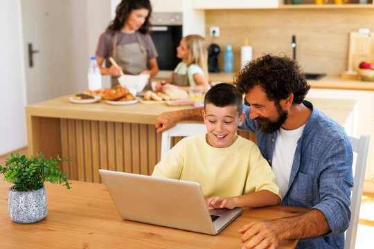 Boy using laptop with father at home