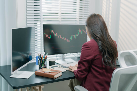 A businesswoman is analyzing stock trading charts on a computer screen in an office; the image shows a female investor analyzing data and working with the cryptocurrency exchange market.