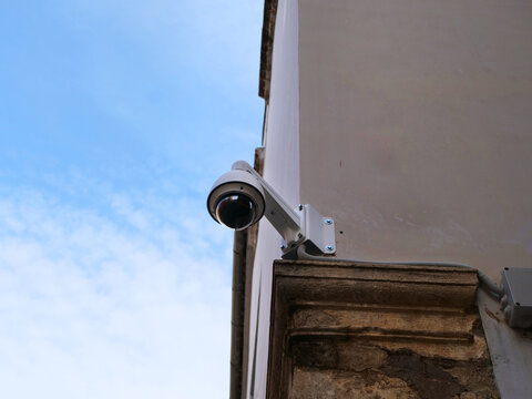 White dome cctv camera mounted on building corner under bright blue sky. Great concept for smart home video monitoring ads, private property protection solutions or urban surveillance article header