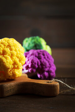 Multicolored cauliflower on a wooden table. Purple, yellow, and green florets.