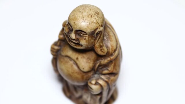 A smiling Buddha figurine sitting on a white surface, great for meditation or decoration. Rotating in a circle