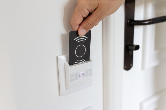 close up of a hand inserting key card into hotel room energy switch holder