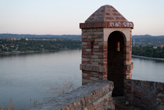 Small brick watchtower sits on Petrovaradin Fortress wall overlooking Danube river at dusk. Novi Sad, Serbia