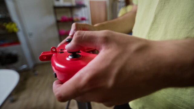 Male operating red remote controller with joysticks, testing robotic device. Footage is perfect for tech education, robotics engineering, or drone piloting promos