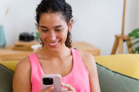 A Hispanic woman happily uses her smartphone