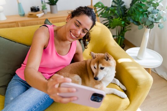 Hispanic Woman taking a selfie with her medium-sized dog on a yellow