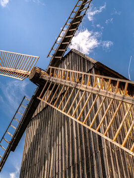 Rustic Wooden Windmill With Sunlit Sails Against A Clear Blue Sky In Countryside