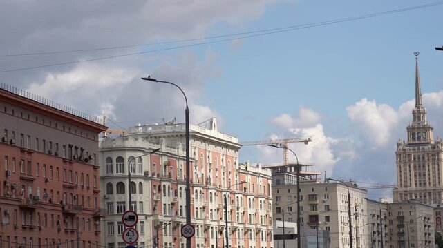 Panoramic city street with historic apartment facades, lampposts, traffic signs, and rooftop construction crane under partly cloudy sky, with city, street, building, architecture detail