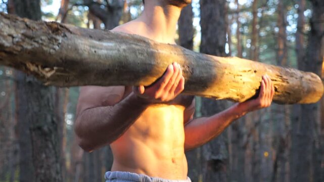 Close up muscular body of man lifting hard weight training biceps. Strong guy working out outdoor. Athlete exercising in nature using log. Concept of sport and active lifestyle. Slow motion Close up
