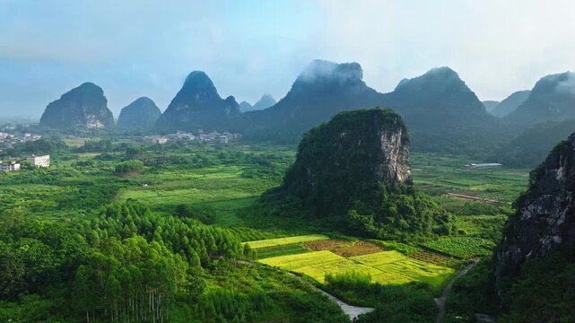 Aerial drone view of a solitary karst hill standing in a green agricultural valley in Guilin, China.