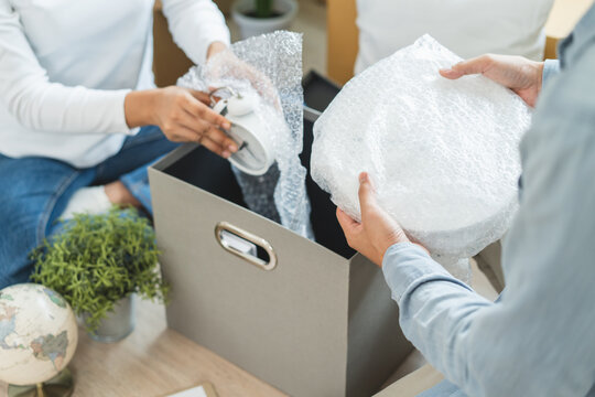 Happy woman checking stuff in cardboard box before sent to transportation company and moving to new location apartment.
