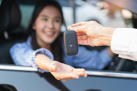 Close up woman hand receiving car remote control from auto dealer rental shop.