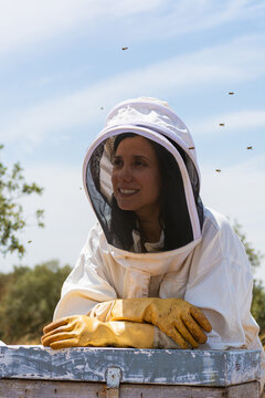 Woman beekeeper wearing protective suit working with bees