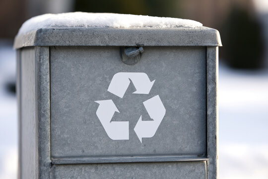 Clothing donation bin winter front view showing weather sealed metal drop box with white recycling symbol and snow covered lid for circular reuse