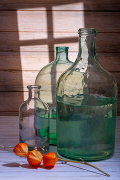 A physalis branch and glass jars on a wooden board background