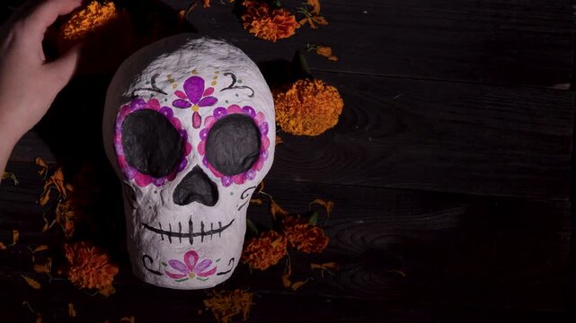 Dia de Muertos Sugar Skull Decor on Dark Wood with Marigold Petals and Hands