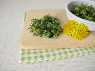 Fresh dandelion buds from the meadow on a wooden cutting board © Heike Rau