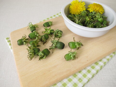 Fresh dandelion buds from the meadow on a wooden cutting board