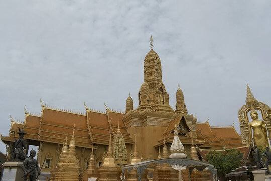 spectacular golden oriental temple sanctuary featuring a massive central prang spire tiered tiled roofs smaller golden stupas and buddha statue