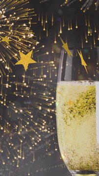 Animation of gold stars falling over two toasting glasses of champagne with bottle and fireworks