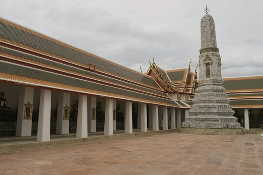 traditional carved stone prang tower and surrounding cloister gallery inside wat pho temple courtyard in bangkok