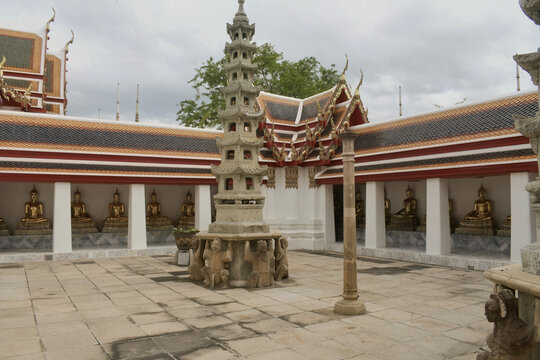 historic courtyard at wat pho in bangkok featuring a carved stone chinese pagoda surrounded by a cloister of golden buddha statues