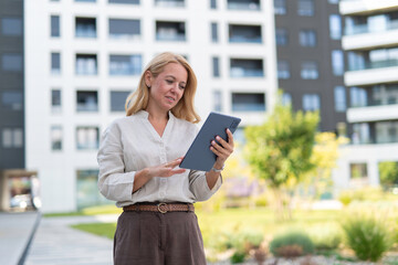 Businesswoman using digital tablet outdoors near modern building © Dexon Dee