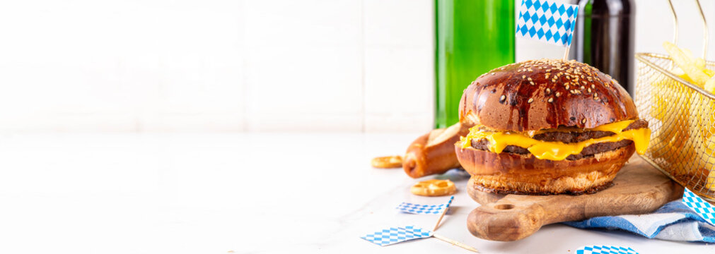Oktoberfest Burger menu with french fries, pretzels, beer bottles. Tasty cheese hamburger in pretzel bun, with french fries, bavarian beer snacks, with checkered tablecloth and Oktoberfest decor