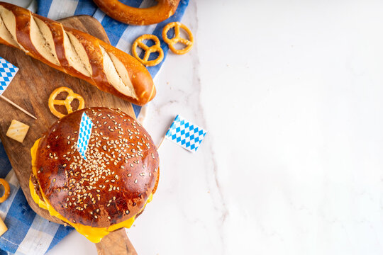 Oktoberfest Burger menu with french fries, pretzels, beer bottles. Tasty cheese hamburger in pretzel bun, with french fries, bavarian beer snacks, with checkered tablecloth and Oktoberfest decor