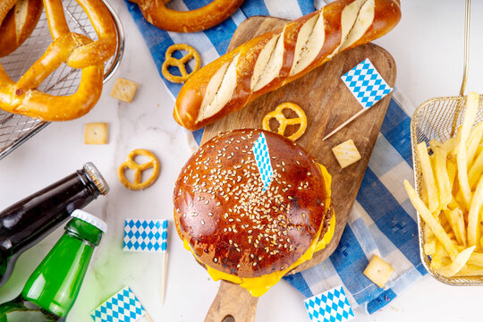 Oktoberfest Burger menu with french fries, pretzels, beer bottles. Tasty cheese hamburger in pretzel bun, with french fries, bavarian beer snacks, with checkered tablecloth and Oktoberfest decor