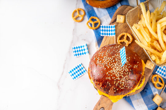Oktoberfest Burger menu with french fries, pretzels, beer bottles. Tasty cheese hamburger in pretzel bun, with french fries, bavarian beer snacks, with checkered tablecloth and Oktoberfest decor
