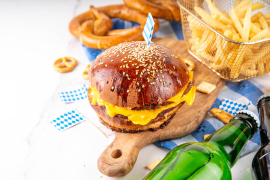 Oktoberfest Burger menu with french fries, pretzels, beer bottles. Tasty cheese hamburger in pretzel bun, with french fries, bavarian beer snacks, with checkered tablecloth and Oktoberfest decor