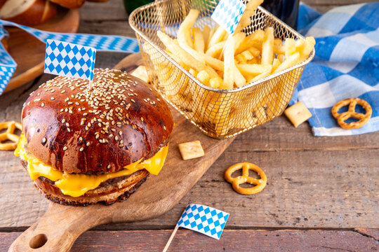 Oktoberfest Burger menu with french fries, pretzels, beer bottles. Tasty cheese hamburger in pretzel bun, with french fries, bavarian beer snacks, with checkered tablecloth and Oktoberfest decor