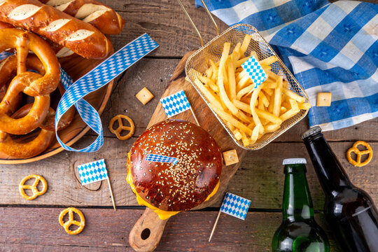 Oktoberfest Burger menu with french fries, pretzels, beer bottles. Tasty cheese hamburger in pretzel bun, with french fries, bavarian beer snacks, with checkered tablecloth and Oktoberfest decor