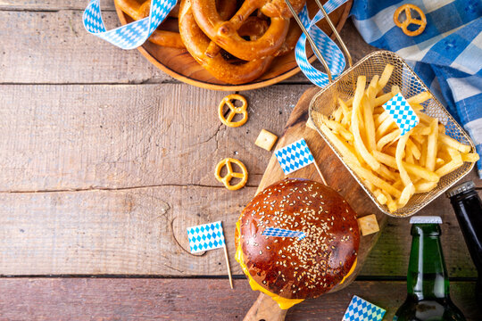 Oktoberfest Burger menu with french fries, pretzels, beer bottles. Tasty cheese hamburger in pretzel bun, with french fries, bavarian beer snacks, with checkered tablecloth and Oktoberfest decor