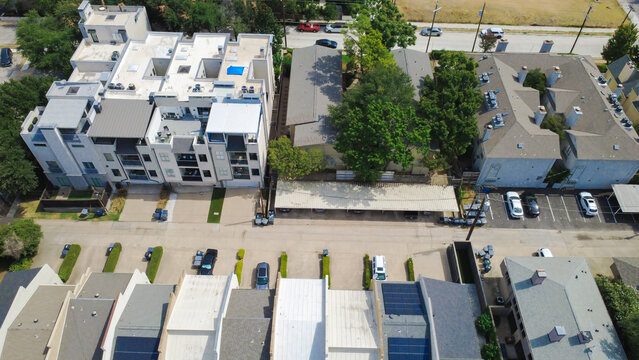 Symmetrical residential roofs line Welborn Street in Dallas. Dark photovoltaic solar panels border parallel paved carport parking rows, DFW Suburban Area, North Texas